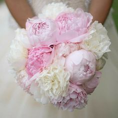 a bride holding a bouquet of pink and white peonies in her wedding dress