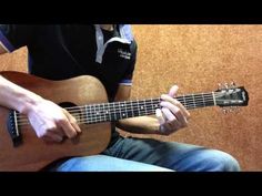 a man sitting down playing an acoustic guitar