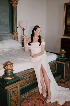 a woman in a white dress sitting on a bed