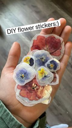 a person holding flowers in their hand with the words diy flower stickers on it