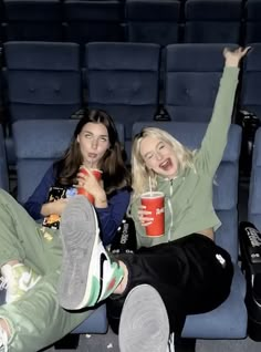 two women sitting on the floor with their feet up and one holding a drink in her hand