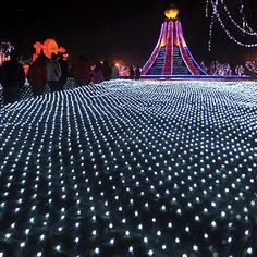 people are standing in the middle of a field covered with lights