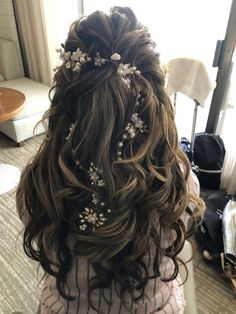 the back of a woman's head with long hair and flowers in her hair