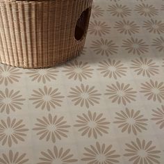 a basket sitting on top of a floor next to a white and brown wallpaper