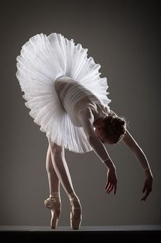 a ballerina in white tutu and ballet shoes doing a handstand pose