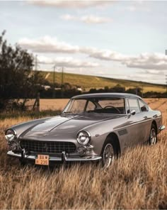 an old car is parked in the middle of some tall brown grass and has a license plate on it