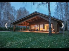 a small cabin in the middle of a forest at night with lights on and open patio area