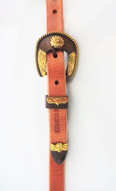 A double ear headstall made in our West Coast Tack Leather Shop. Hermann Oak harness leather. 5/8 inch in width. Brown Iron buckles and matching conchos with brass rope edge and flower. The pattern name is San Pablo. Hansen Western Gear. Sliding ear pieces can be removed if you only want a single ear. Hand edged and rubbed. Average horse size. We have many leather and buckle options please feel free to contact us with custom requests Southwestern Hand Tooled Leather Belt Buckles, Adjustable Brown Bridle Leather Belt Buckles, Hand Tooled Leather Belt Buckles For Ranch, Adjustable Traditional Leather Belt Buckles, Adjustable Leather Belt Buckles, Traditional Style, Traditional Leather Belt Buckle, Adjustable, Adjustable Leather Belt Buckles In Traditional Style, Adjustable Brown Belt Buckles For Rodeo, Adjustable Leather Belt Buckles For Western-themed Events