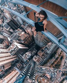 a woman standing on top of a tall building in the middle of a large city