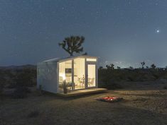 a small white house sitting in the middle of a field under a night sky filled with stars