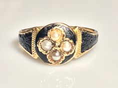 Lovely antique black enamel seed pearl momento mori ring ring in 15K yellow gold from the Victorian era. This beautiful ring has it's original Victorian 188(4?) hand engraving, full British assay marks for 1881 and original makers mark. In excellent condition with decorative floral repousee' covered with black enamel, as was traditional during the time. Four natural seed pearls in the middle. The top of the ring measures 9.7mm at its the center. The diameter of the circle area on top is 9.7mm. M Antique Yellow Gold Enamel Ring, Antique Engraved Yellow Gold Enamel Ring, Victorian Hallmarked Enamel Ring For Wedding, Victorian Enamel Ring For Anniversary, Victorian Style Hallmarked Enamel Ring For Wedding, Victorian Style Hallmarked Enamel Ring For Anniversary, Antique Round Enamel Ring, Elegant Enamel Signet Ring, Victorian Yellow Gold Enamel Ring