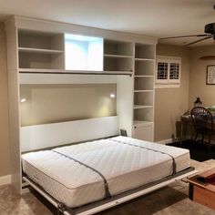 a bed that is in the middle of a room with a book shelf above it