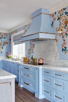 a kitchen with blue cabinets and white counter tops, gold trimmings on the backsplash