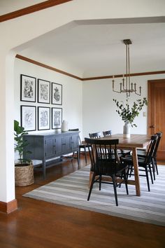 a dining room table and chairs with pictures on the wall behind it in an open space