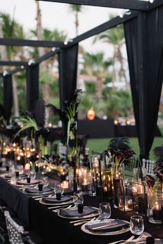 a long table is set with candles and black linens for an elegant dinner party