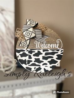 a sign that says welcome to simply raelieigh's on it with a cow print bow