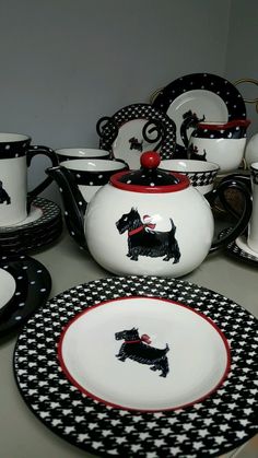 a table topped with black and white dishes covered in cups and saucers filled with dogs