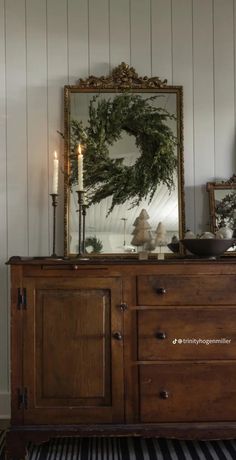 a dresser with a mirror and candles on it