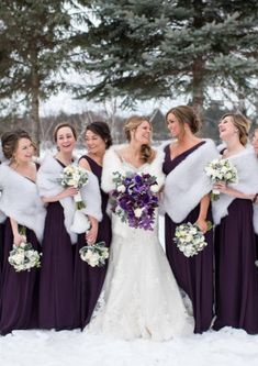 a bride and her bridals standing in the snow with their fur stolers