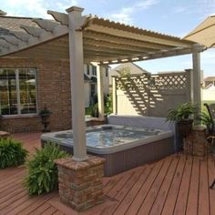 a hot tub sitting on top of a wooden deck next to a patio with an umbrella