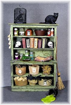 an old green shelf filled with books and other items next to a cat figurine