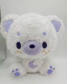 a white teddy bear sitting next to a silver box with a purple heart on it