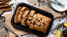 sliced banana bread sitting on top of a cutting board next to bananas and other food