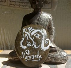 a buddha statue sitting next to a rock with the words namaste painted on it