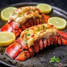 two lobsters on a plate with lemon wedges and parsley garnish