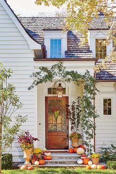 a white house with pumpkins and gourds on the front steps in front of it