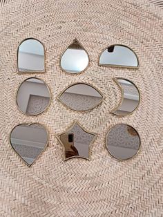 six mirrors arranged in the shape of hearts on a wicker tablecloth with an oval mirror above them