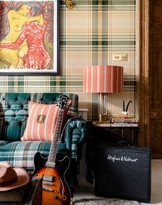 a living room filled with furniture and a guitar in front of a painting on the wall