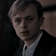 a young man in a suit and tie looking at the camera with an intense look on his face