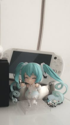 an anime figurine sitting on top of a table next to a nintendo wii game controller