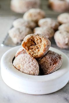 powdered sugar covered doughnuts in a white bowl on a marble countertop