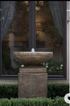 a stone fountain in front of a window