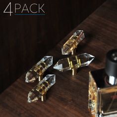 four clear glass knobs on a wooden table next to a bottle of cologneine