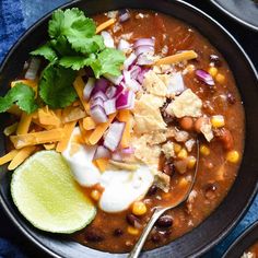 a black bowl filled with chili, cheese and tortilla chips on top of a blue towel