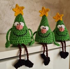 three crocheted christmas trees sitting on top of a white shelf