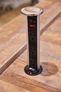 an electronic device is sitting on top of a wooden table with a red light in the middle