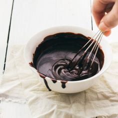 someone is whisking chocolate in a bowl on a white tablecloth with napkins