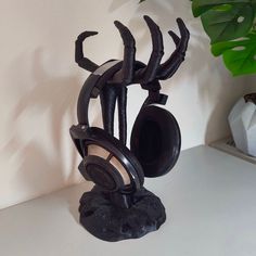 there is a black sculpture with headphones in it on the table next to a potted plant