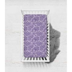 a baby's crib with a purple and white floral print on the cover