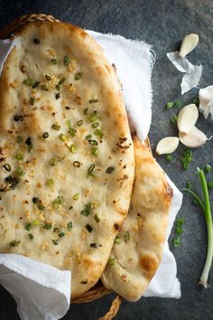 two pita breads sitting on top of a table next to garlic and green onions