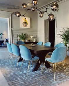 a dining room table with blue chairs and lights above it, on an instagram page