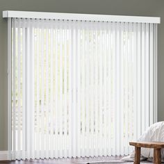 a bedroom with white vertical blinds and a wooden bench in front of the window,