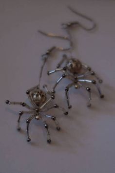 two silver spider earrings sitting on top of a table