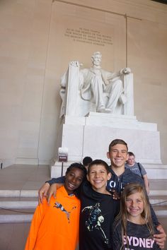 a group of kids standing in front of the lincoln memorial with their arms around each other