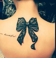 the back of a woman's neck with a bow tattoo