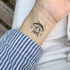 a mushroom tattoo on the wrist is shown in black ink, with stars around it